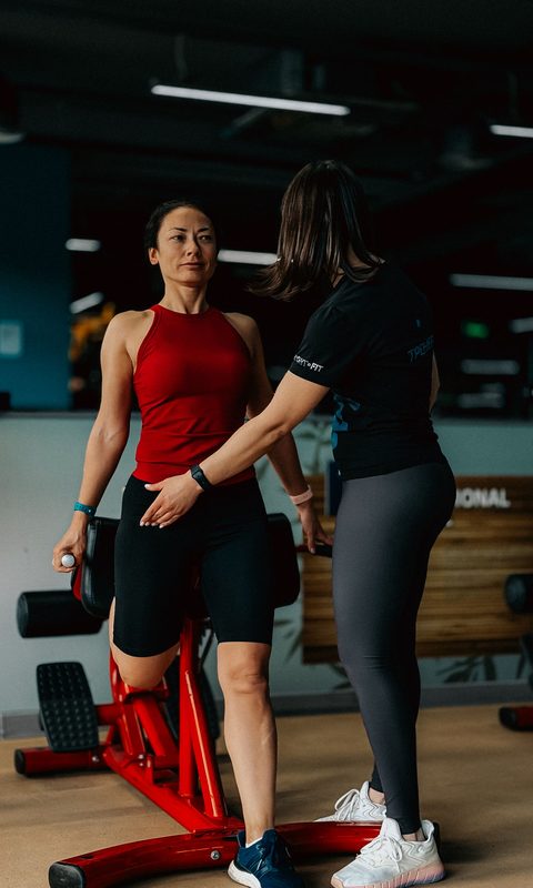 Trainer guiding a client through a machine set-up